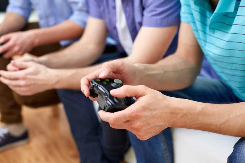 Three people, lost in the grip of video game addiction, sit on a couch intensely focused, each clutching their game controllers.